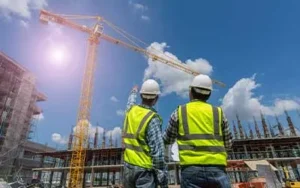 Two construction workers stand on site